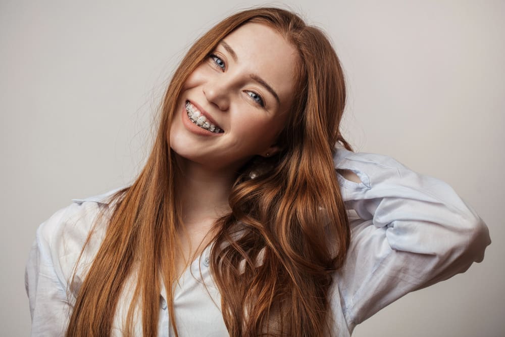 A smiling individual with what appear to be clear braces poses. Orthodontic solutions like these may be offered by practitioners in Henderson, NV.