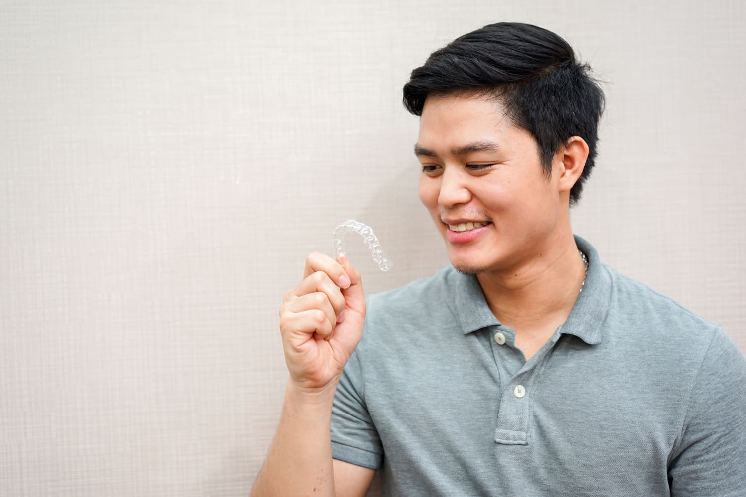A Person smiling proudly presents a clear dental aligner hold with her hand, reminiscent of modern invisalign at Chauncey Orthodontics in Henderson, NV.